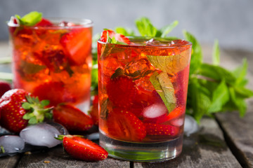 Strawberry mojito and ingredients on rustic background