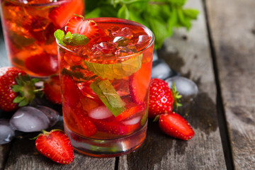 Strawberry mojito and ingredients on rustic background