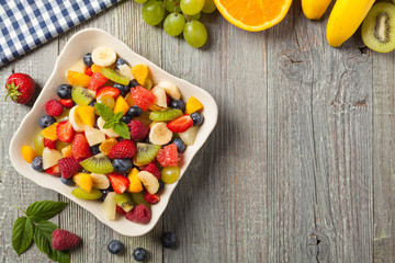 Delicious fruit salad with fresh fruit. Wooden, gray table in the background.