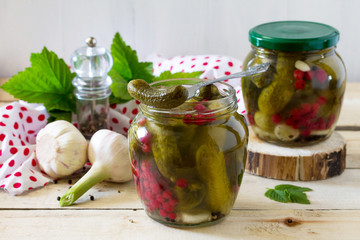 Marinated cucumbers gherkins. Marinated pickled cucumbers with red currant berries and spices on the kitchen wooden table.