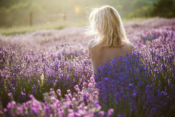 Fototapeta na wymiar Naked woman posing in lavender field at sunset