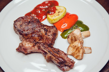 Steak with vegetables grilled served on a white plate.