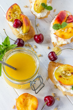 Homemade fresh sweet toasted toast with fruit. Peach and cherry sandwiches with nuts and honey on a white wooden table. The concept of a healthy diet and diet.