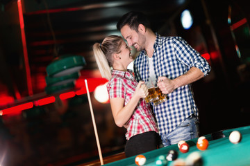 Fototapeta na wymiar Young couple playing together pool in bar