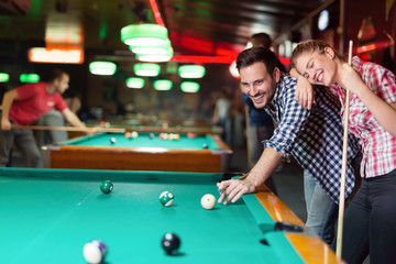 Young couple playing together pool in bar