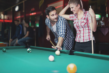 Fototapeta premium Young couple playing together pool in bar