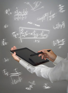 Man scientist or student holding tablet PC and working with various high school maths and science formulas.