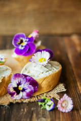 Fototapeta na wymiar Sandwich with herb and edible flowers butter on marble cutting board. Healthy food.