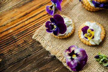 Sandwich with herb and edible flowers butter on wooden background, healthy food.