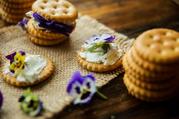 Sandwich with herb and edible flowers butter on wooden background, healthy food.