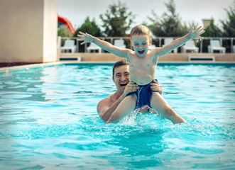 Naklejka premium Father and son funny in water pool under sun light at summer da