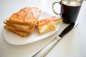 Tasty breakfast. Toasts with butter and jam on a plate. Cup of coffe.
