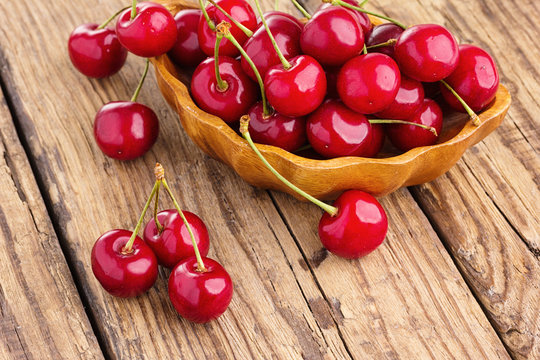 Fresh cherry in bowl on wooden background.