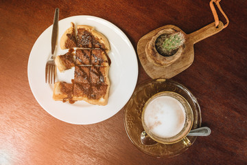 Hot coffee with bread on wooden table background.