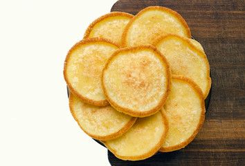 Golden pancakes lined in the shape of a flower on a wooden board, without decorations.