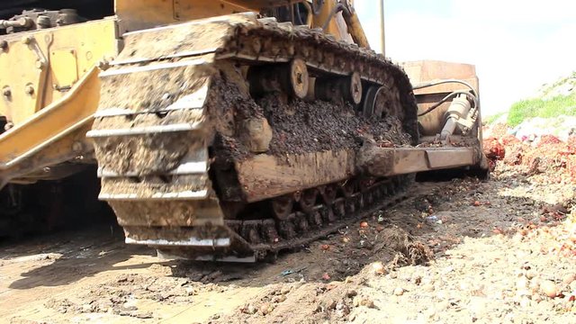The bulldozer is slowly moving off-road, the bucket and caterpillars of the excavator are taken off close-up