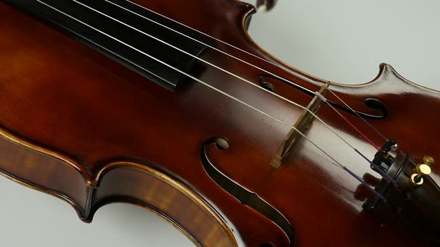 Close up soundboard of violin and bow. The bow moves along the violin string