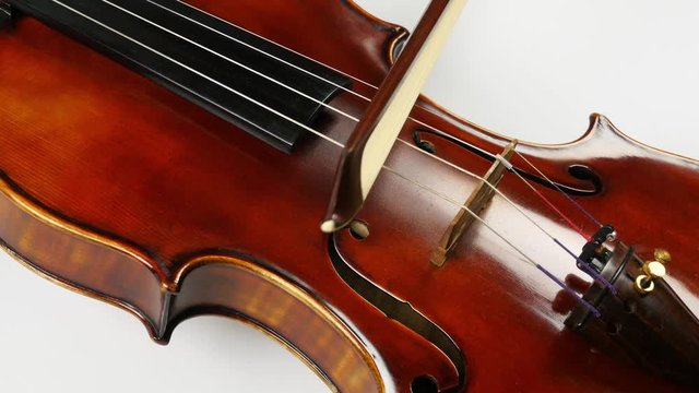 The bow moves along the violin strings. Brilliant beautiful wood of the violin deck. Closeup