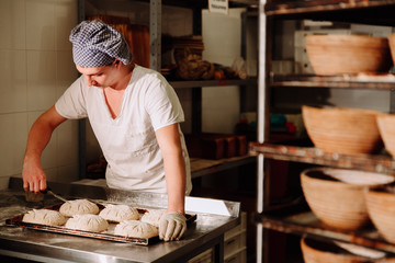 a Baker makes manual incisions on the dough for the bread. The Manufacture Of Bread.Bakery