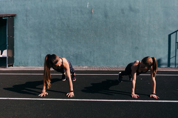  Two athletic sisters doing press ups outdoors. sport and training. Sport tight clothes. Sporty girls. Fitness concepts. Outdoor