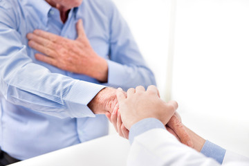 Doctor holding senior male patient hand with care