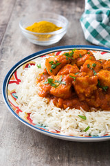 Chicken tikka masala with basmati rice on wooden table
