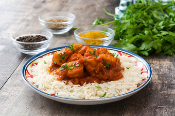 Chicken tikka masala with basmati rice on wooden table

