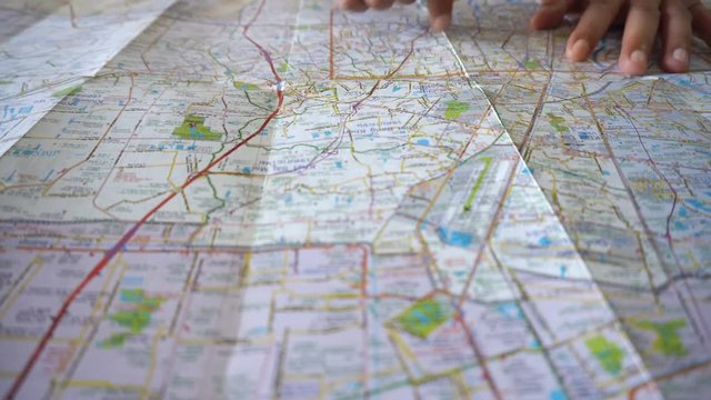 Dolly shot of man's hand drawing on map by finger
