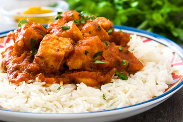 Chicken tikka masala with basmati rice on wooden table
