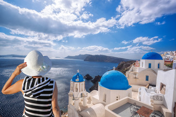 Woman with hat watching Oia village on santorini island in Greece
