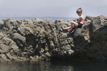 Fototapeta na wymiar Girl climbed on some rocks