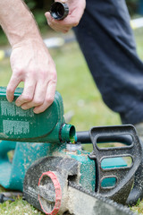 Handyman replenishes the oil in chain saw for chain maintenance