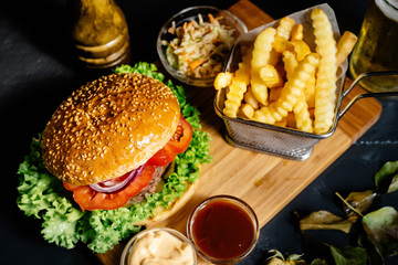 Tasty american stylish beef burger with grilled meat and mayo served with fries, coleslaw and beer