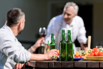 happy family talking while having lunch on patio at daytime. Selective focus on bottles