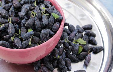 Ripe honeysuckle (lonicera) in a bowl on the table.