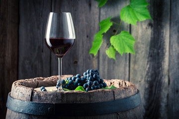 Glass of red wine and on old oak barrel © shaiith
