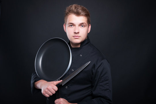 Cook with knife and pan posing confident