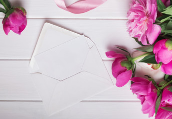 Beautiful peonies and blank paper in envelope