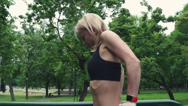 Young girl doing push-ups on the parallel bars. Summer workout
