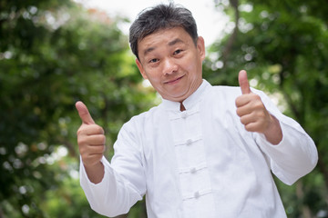 asian kung fu senior man showing thumb up hand gesture