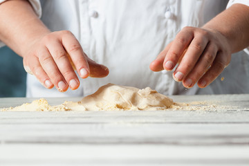 Closeup hand of chef baker in white uniform making pizza at kitchen