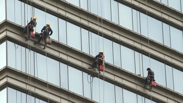 Climber cleaning modern building glass wall 