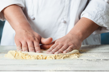Closeup hand of chef baker in white uniform making pizza at kitchen