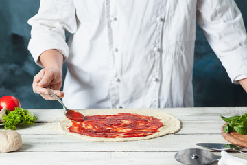 Closeup hand of chef baker in white uniform making pizza at kitchen