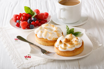 Lemon tart with meringue and berry mix, coffee  close-up. horizontal