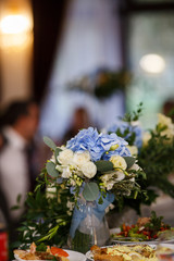 Bride's bouquet made of roses and hydrangeas stands in the vase on dinner table