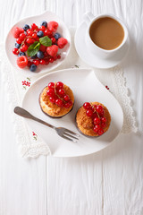 Coconut muffins with berries and coffee with milk close-up on the table. vertical top view