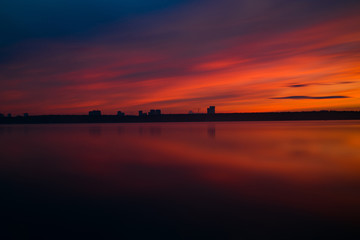 Obraz premium Orange and red sunset at coast of the lake