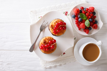Coconut muffins with berries and coffee with milk close-up on the table. Horizontal top view