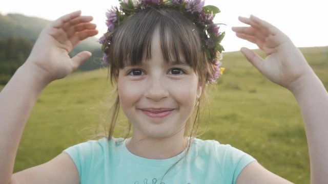 Pportrait of cute young smiling girl with flowers wreath on her head